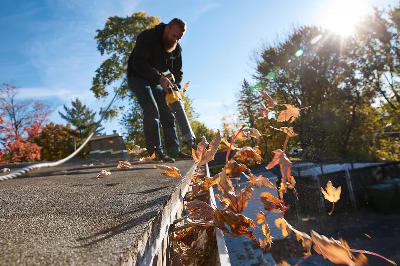 Clearing fall leaves and debris from a roof and gutters